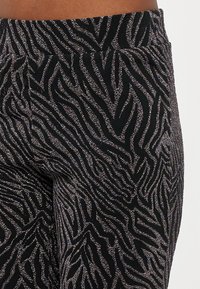 Crne tajice s glitter uzorkom zebre, sa mekanom teksturom i udobnim, rastezljivim pojasom.