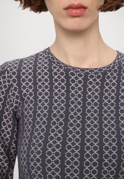 Top navy con scollo rotondo, caratterizzato da un motivo circolare ripetitivo in un tenue rosa chiaro. Tessuto morbido, design aderente, dettagli minimi.