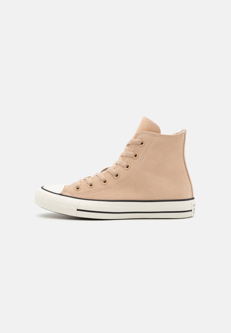 Zapatilla alta de lona beige con una puntera de goma blanca, rayas negras a lo largo de la suela y cordones redondos. Textura suave, diseño minimalista.