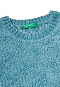 Jasnoniebieski sweter dzianinowy z fakturowanym wzorem w warkocze, z ribbowanym dekoltem oraz zieloną metką z napisem "United Colors of Benetton."