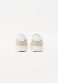 Sneaker bianchi e beige con tomaia in pelle liscia, dettagli in suede, suola chunky e design minimalista.