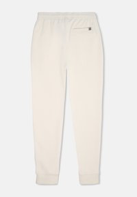 Krämfärgade joggerbyxor i mjukt tyg med elastisk midja, muddar vid anklarna och en liten sidoficka som har en randig detalj.