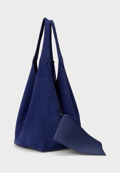 Sac tote en daim bleu marine avec une forme triangulaire, deux longues poignées et une pochette en cuir bleu marine amovible avec fermeture éclair.