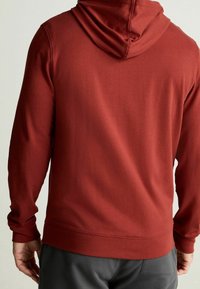 Sudadera con capucha color burdeos, de mangas largas y puños acanalados. Textura suave y ajuste relajado, combinada con pantalones grises.