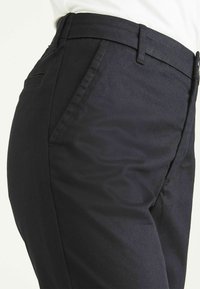 Navy tailored trousers with a smooth texture, featuring side pockets and a straight fit, showing waistband and stitching details.