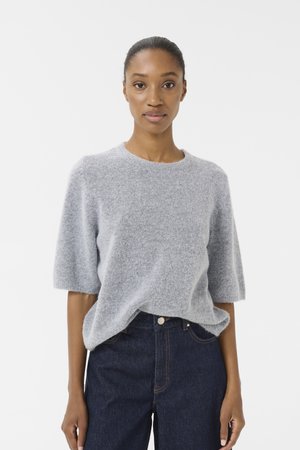 Light gray, short-sleeve sweater made of soft, fuzzy material with a round neckline. Worn with dark denim jeans.
