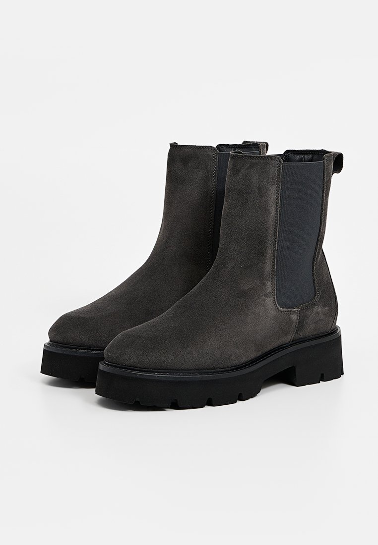 Szare zamszowe botki za kostkę z elastycznymi panelami bocznymi, masywną czarną podeszwą i czystym, minimalistycznym designem, co ułatwia noszenie.