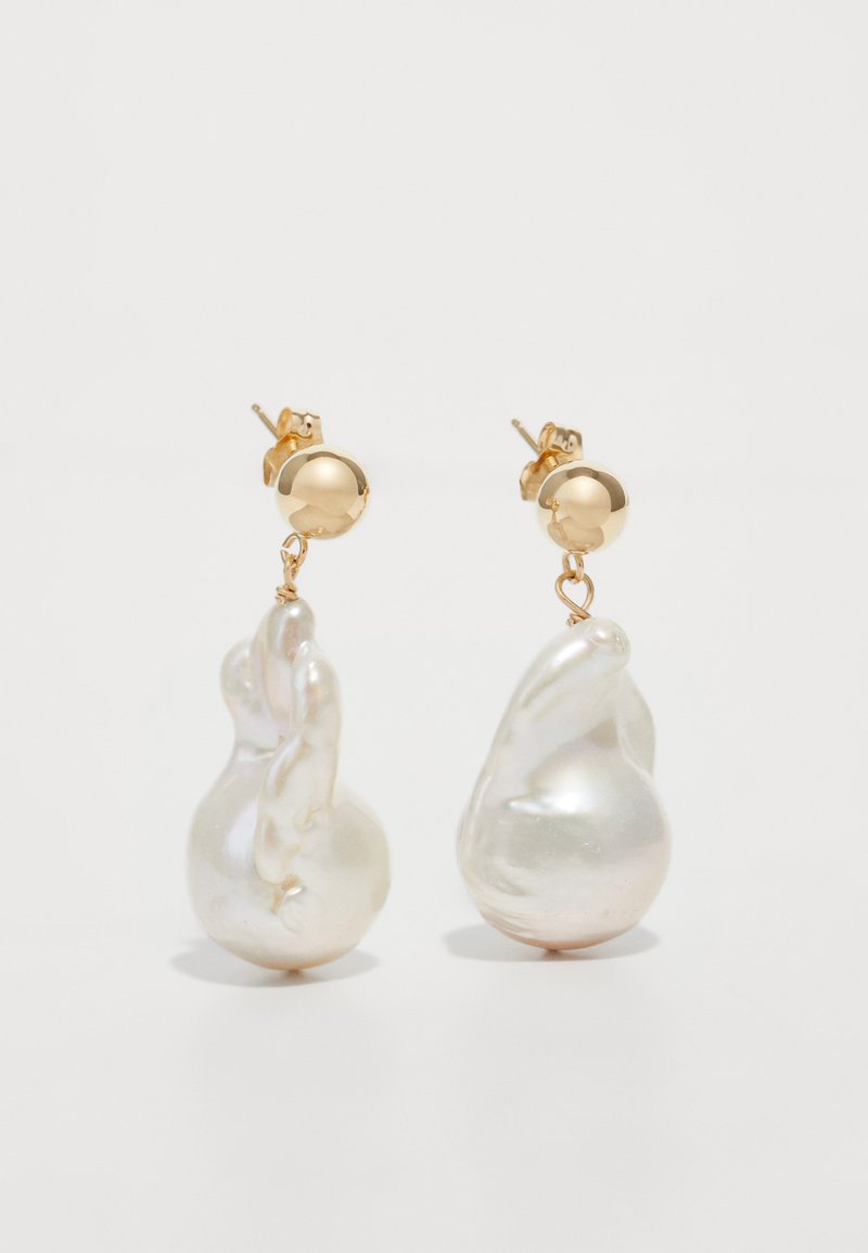 Brincos em ouro com pérolas brancas irregulares e lustrosas. As pérolas apresentam superfícies suaves e formas orgânicas, criando designs únicos.