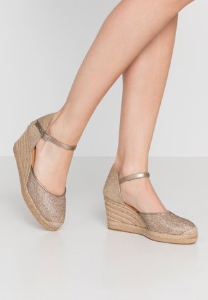 Talons compensés de couleur bronze métallique clair avec une tige en tissu texturé et une plateforme en jute tressé ; dotés d'une bride à la cheville avec une boucle argentée.