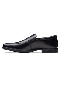 Schwarzer Leder Slipper mit spitzem Schuhdesign, glänzender Oberfläche, dezenten Steppnähten und einer flachen Gummisohle.