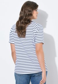 Pruhované tričko s námořnickou modrou a bílou horizontální pruhovanou strukturou, krátkými rukávy, kulatým výstřihem a volným střihem, kombinované s modrými džínami.