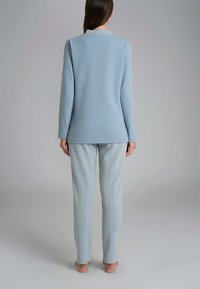Set di abbigliamento da casa di un blu chiaro, composto da una maglia a maniche lunghe con scollatura rotonda e pantaloni leggermente affusolati con motivo a spina di pesce.