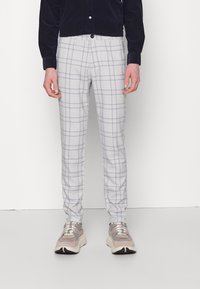 Ljusgrå rutig byxor med slim fit, tillverkade av vävt tyg med en subtil textur, i kombination med ljusa sneakers.