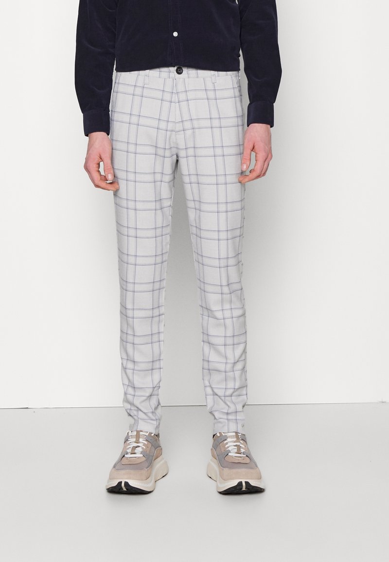 Ljusgrå rutig byxor med slim fit, tillverkade av vävt tyg med en subtil textur, i kombination med ljusa sneakers.