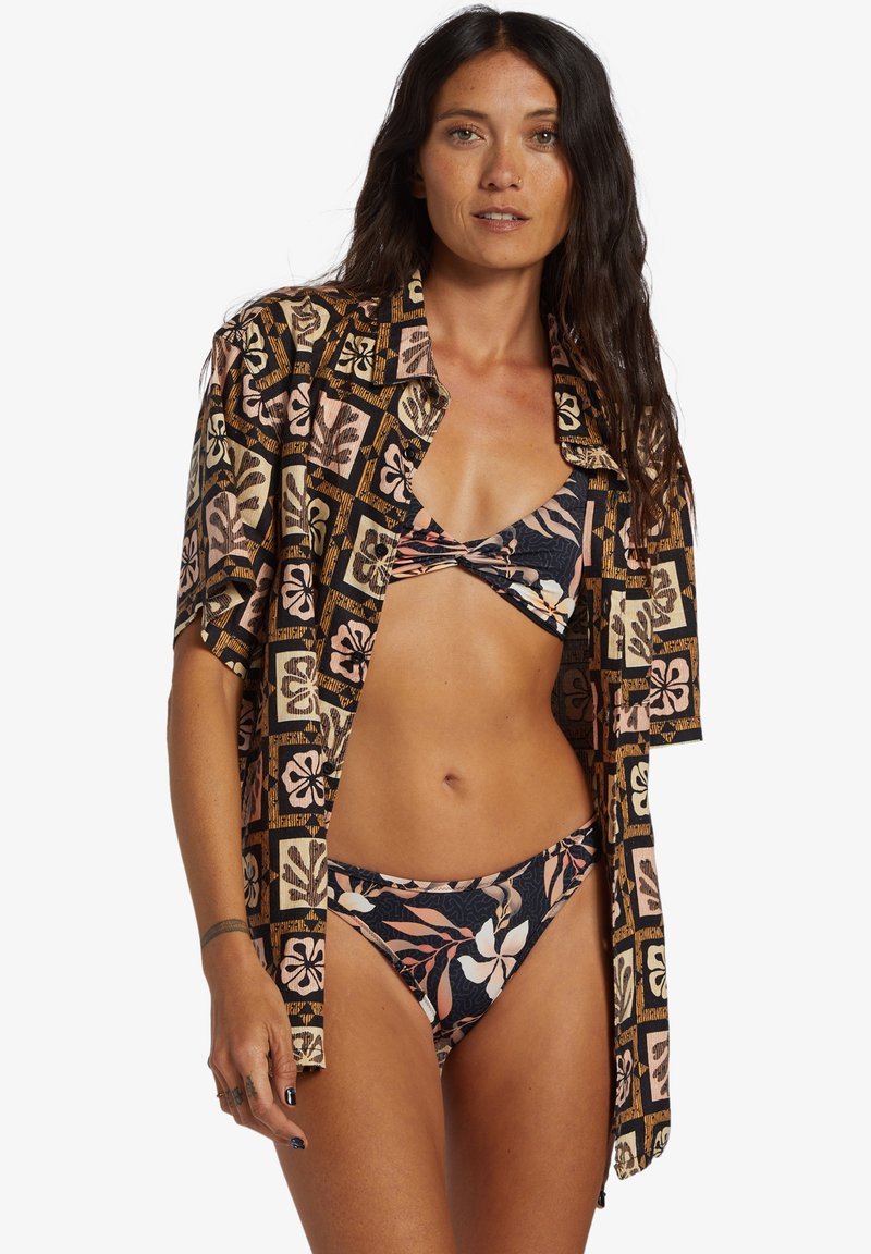 Floral-patterned bikini set in navy and pink, paired with a short-sleeve button-up shirt featuring a patterned design on a black background.