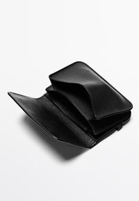 Czarny skórzany portfel o gładkiej fakturze, z trójdzielnym rozkładem i widocznym przeszyciem. Otwarty, ukazujący wiele kieszeni na karty i przegródek.