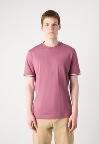 T-shirt s kratkimi rokavi in krožnim izrezom iz stisnjenega roza bombaža. Ima kontrastne črno-bele črtaste poudarke na rokavih. Gladka tekstura.