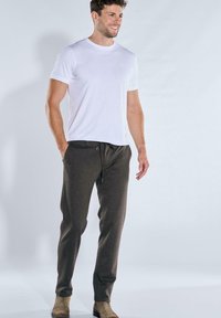 White short-sleeve t-shirt with small logo, paired with dark brown tapered sweatpants featuring a drawstring and side pockets.