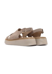 Sandali in suede beige con design aperto, cinturino alla caviglia regolabile e suola platform. Presentano un'accenno di cucitura lungo il bordo esterno.