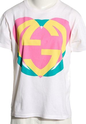 Biały t-shirt z krótkim rękawem z nakładającymi się na siebie różowymi, żółtymi i morsko-zielonymi kształtami serc tworzącymi abstrakcyjny wzór na klatce piersiowej.