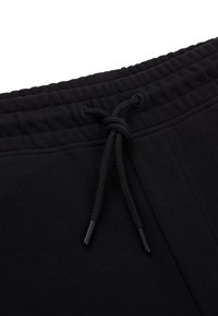 Svarta träningsbyxor med dragsko med metalldelar, ribbad midja och mjuk, slät tygtextur.