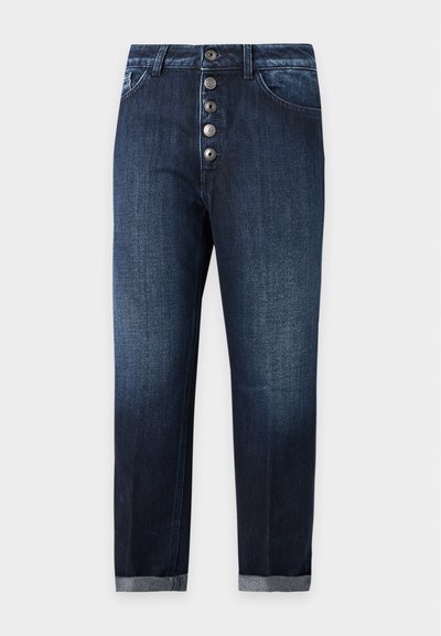 Jean en denim bleu foncé avec une braguette à cinq boutons, poches avant, passants de ceinture et revers roulés aux chevilles, présenté sur un fond uni.