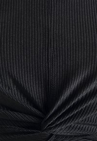 Black ribbed fabric with a subtle sheen, featuring twisted knot detail at the center. Includes visible stitching and lines from the texture.