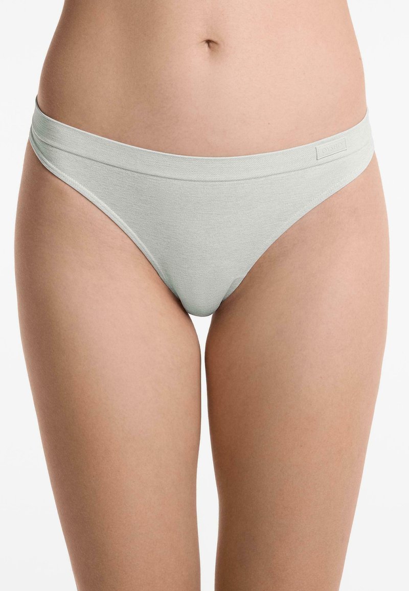 Lichtgrijze katoenen string met zachte stof, brede elastische tailleband en minimalistisch design. Bevat subtiele logo-details op de tailleband.
