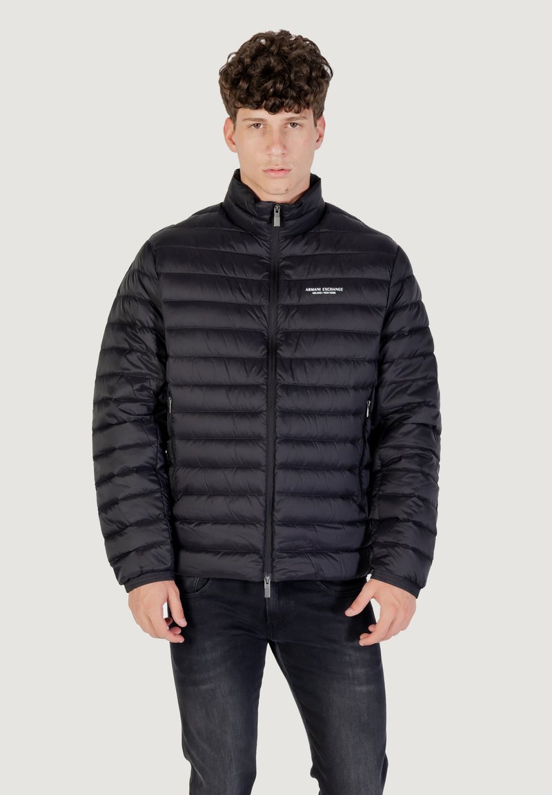 Chaqueta de plumón negra con patrón acolchado horizontal, cuello alto, cremallera frontal y detalle de logo en el pecho. Tejido suave y ligero.