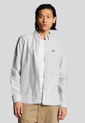 Chemise à manches longues rayée en coton blanc et bleu avec un col boutonné et un logo brodé jaune sur la poche de poitrine.