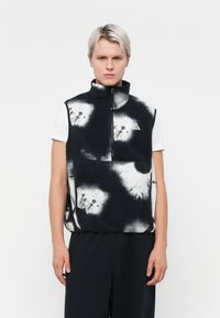 Melnbalts vilnas veste ar augstu apkakli, priekšējo rāvējslēdzēju un lielu kabatu. Iespējots traipveida raksts un trijstūra logo detaļa.