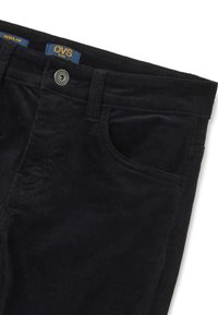 Pantalones de pana negra de corte regular. Cuentan con un botón de metal, un bolsillo frontal y costuras visibles. Textura suave con estrías verticales.