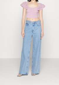 Rosa kort topp med texturerade, frillade ärmar, parat med ljusblå vida jeans. Outfiten har en avslappnad passform och en casual stil.