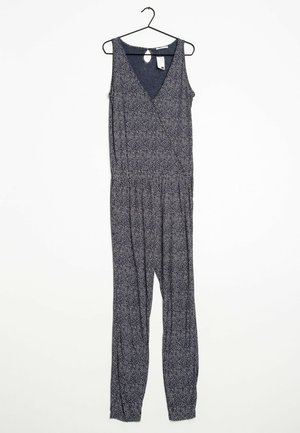 Combinaison sans manches bleu marine avec un décolleté en V, une taille élastique et un petit motif floral blanc. Accrochée à un crochet noir.