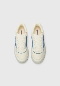 Baltas kedas ar ziliem akcentiem, teksturēta āda, apaļa purngalu, plakani šņores un gumijas zole. "Reebok" logo redzams uz mēles un sānos.