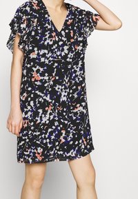 Robe noire à motifs floraux avec un décolleté en V, manches courtes volantes, présentant des motifs colorés en blanc, rose et bleu. Conception légère et décontractée.