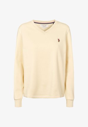 Krēmkrāsas garroku krekls ar V-veida kaklu un ribveida aprocēm, U.S. Polo Assn. etiķete apkakles iekšpusē un mazs izšūts polo spēlētāja logo kreisajā krūšu pusē.