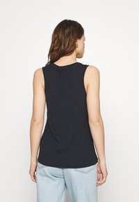 Top senza maniche nero con scollatura tonda, realizzato in tessuto morbido e leggero. Orlo dritto e vestibilità rilassata. Progettato per il comfort.