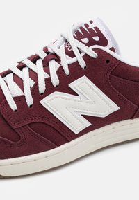 Burgunderfarbene Wildledersneaker mit weißen Schnürsenkeln und Logo. Verfügt über ein strukturiertes Obermaterial, einen gepolsterten Schaftrand und eine hellfarbige Gummisohle.