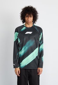 Zwart sporthemd met lange mouwen en teal diagonale strepen. Heeft een ronde halslijn en een wit logo op de borst. Gemaakt van lichtgewicht materiaal.