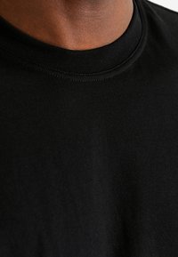 Zwart katoenen t-shirt met een ronde halslijn, ribbeltextuur bij de kraag, met een gladde stof en een schoon, eenvoudig ontwerp.