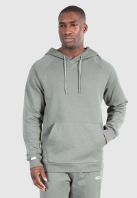 Světlá zelená mikina vyrobená z měkkého materiálu, s přední kapsou, stažitelnou kapucí a pružnými manžetami. Jednoduchý, nezdobený design.
