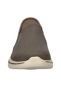 Slip-on shoe made of brown mesh fabric with a beige rubber sole. Features a rounded toe and subtle stitching accents.