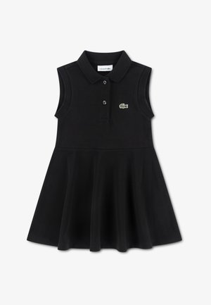 Schwarzes ärmelloses Polokleid aus weichem Stoff. Verfügt über einen klassischen Kragen, eine Knopfleiste und das grüne Lacoste-Krokodil-Logo. Ausgestellter Rock.