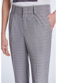 Pantalons à carreaux gris avec une coupe ajustée, dotés d'un devant plat, de poches latérales et de lignes rouge et bleue subtiles dans le motif.