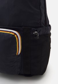 Czarny plecak z teksturowaną, siateczkową boczną kieszenią, wielokolorowymi akcentami zamków oraz solidnym paskiem z plastikową klamrą.