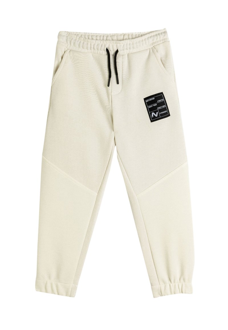Cremefarvede sweatpants med struktureret stof, elastisk talje, sort snor og et sort firkantet logo-patch på venstre lår.