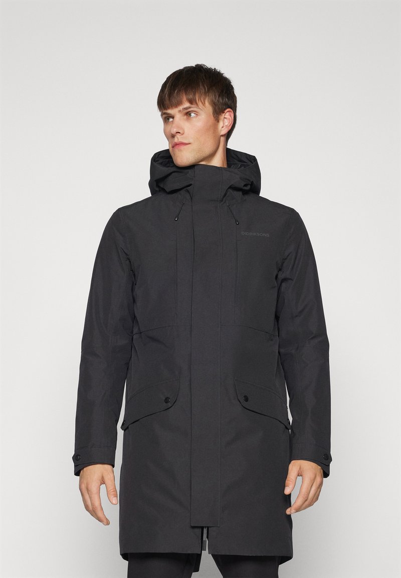 Sort vandtæt parka med hætte, frontlynlås og to store udvendige lommer. Har en glat tekstur og minimal branding.