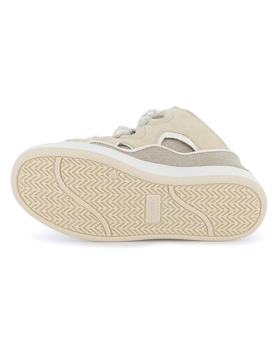 Baskets beiges avec une tige en tissu texturé agrémentée d'accents perforés et une semelle en caoutchouc, présentant un motif de bande de roulement en zigzag.