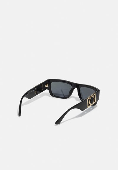 Sorte solbriller med rektangulære linser, glinsende rammer, gullaksonter på siden og mørkt tonede linser. Har et minimalistisk design.